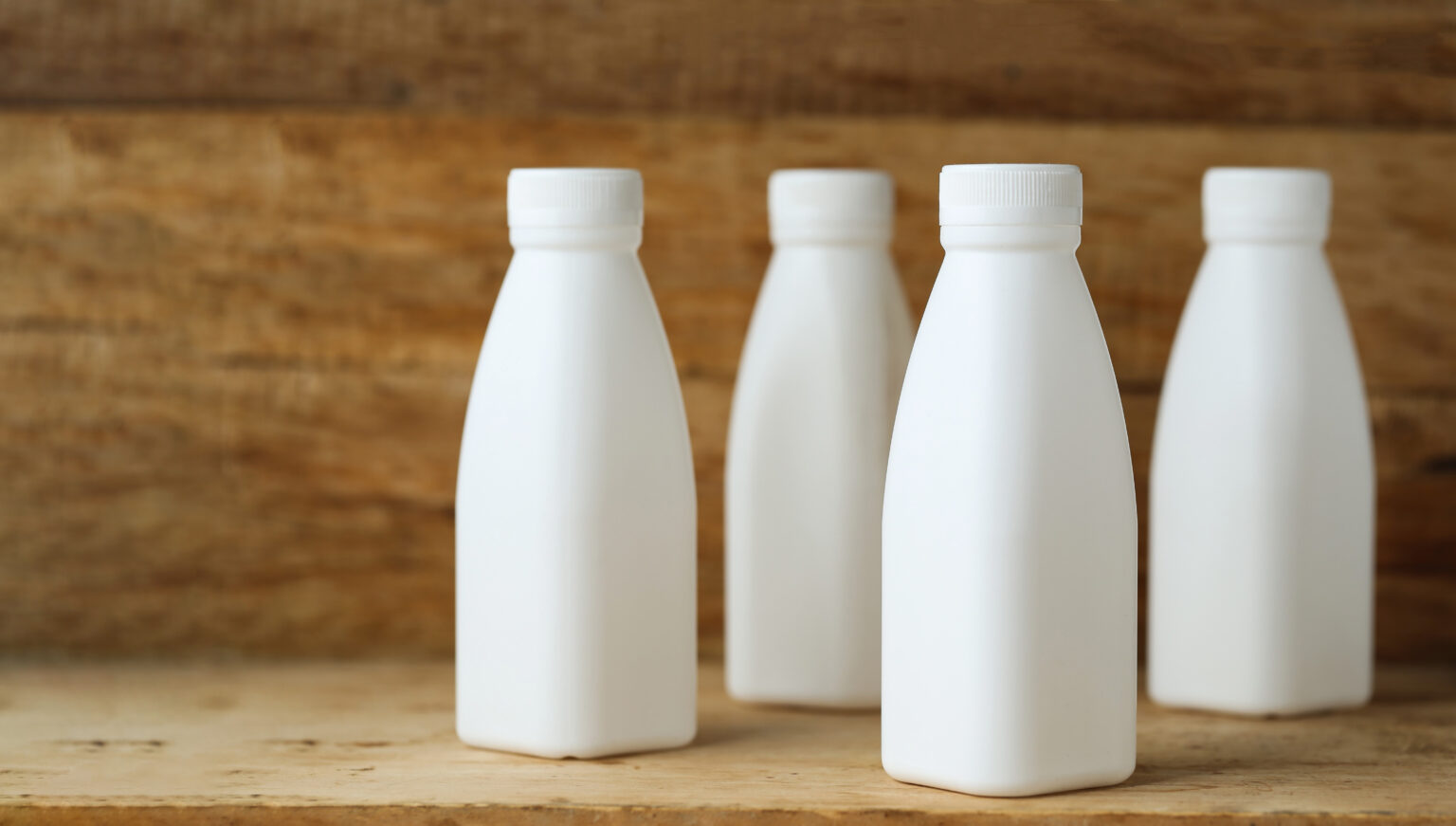 white plastic milk bottles on retro wooden table background